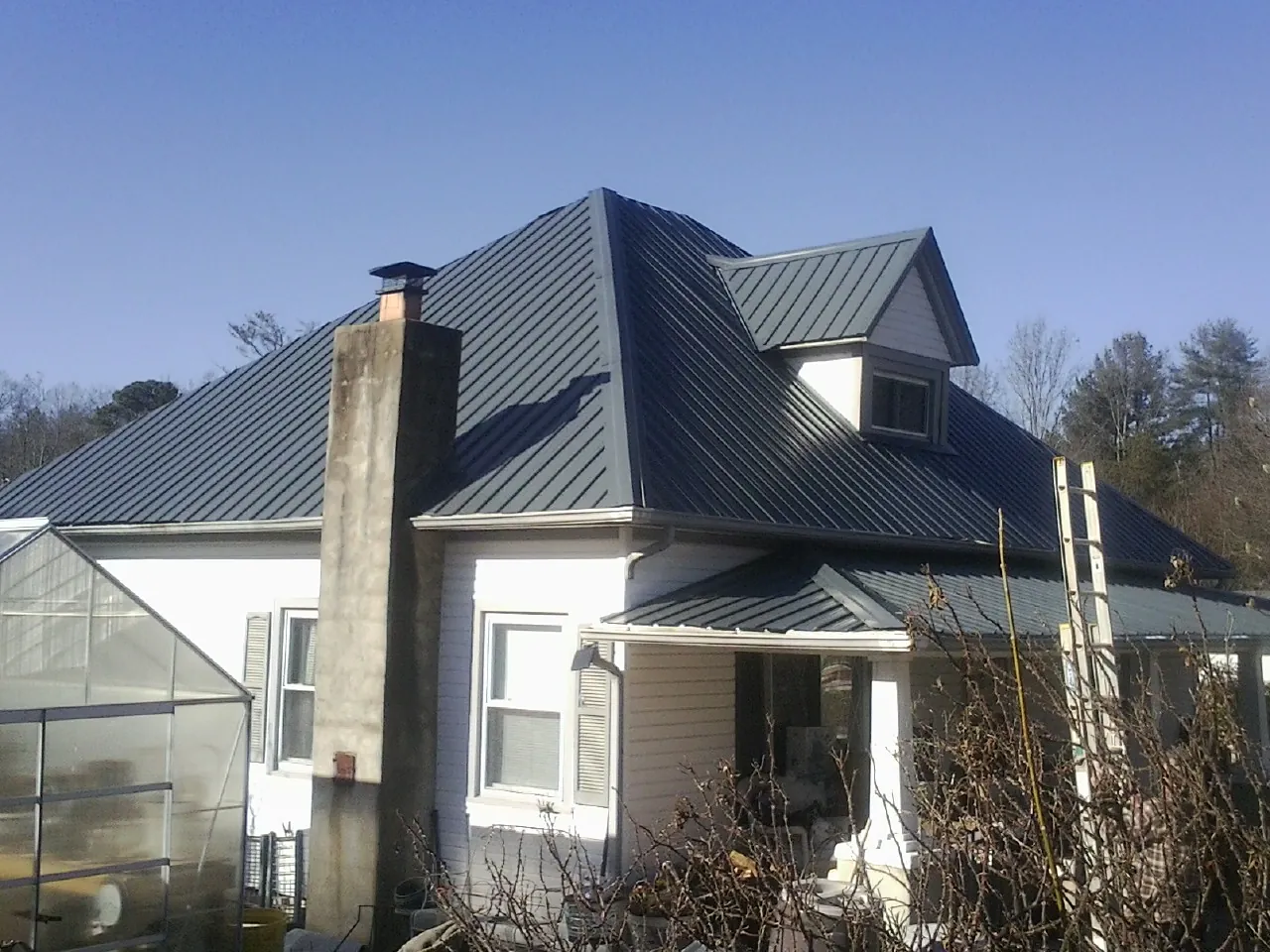 Dark blue standing seam metal roof on a white farmhouse with dormer — Slate & Tile Roof Repair by Roofing Brothers in Nutley