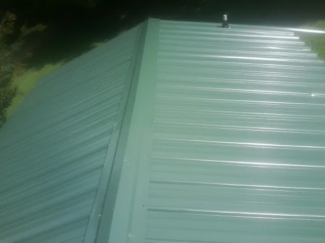 New green metal panels meeting at the ridge of a roof — Flat Roof Repair work by our crew in Nutley