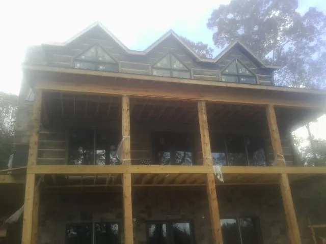 Dormers and porch framing on a large log home under construction — Roof Coating work by our crew in Nutley